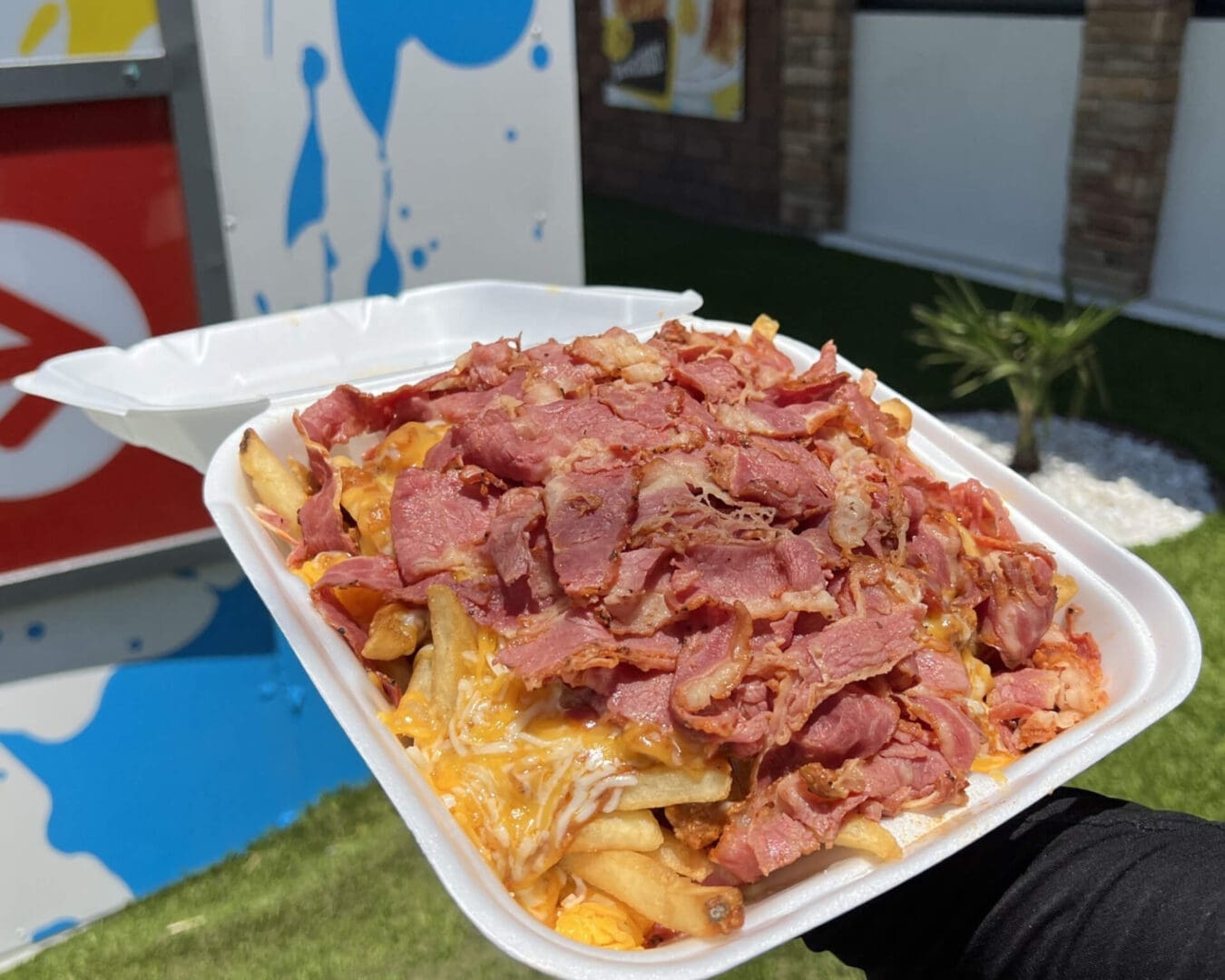 A person holding a tray of food in front of a building.